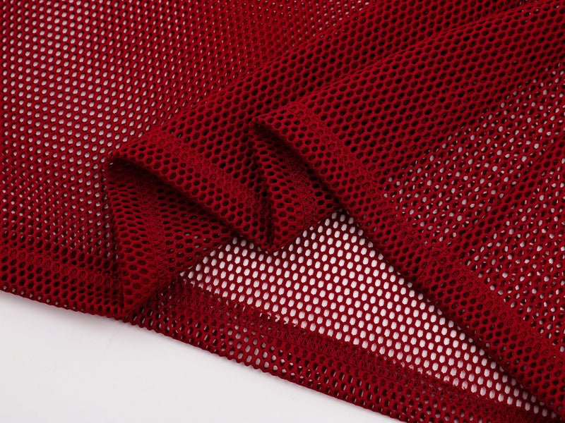 Close-up of red mesh polo tee fabric with breathable open-knit texture and stitched hem detail