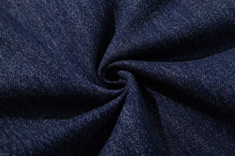 Close-up of mid-blue denim fabric texture folded in a swirl