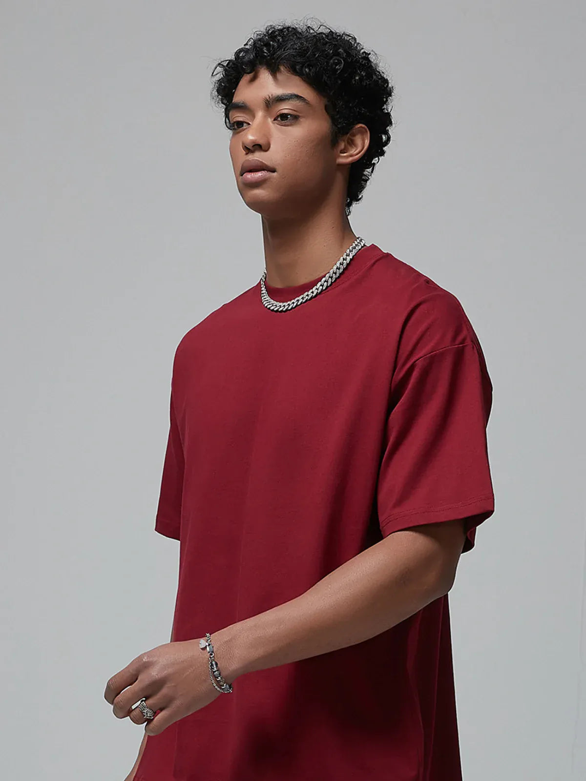 A person wears a Custom Anime Character Burgundy T-Shirt - Personalized 230GSM 100% Cotton Tee, paired with a silver chain necklace and bracelet, standing against a neutral background.