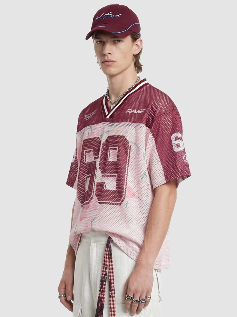 Model wearing a burgundy floral mesh jersey T-shirt with large 69 print, V-neck trim, and streetwear styling