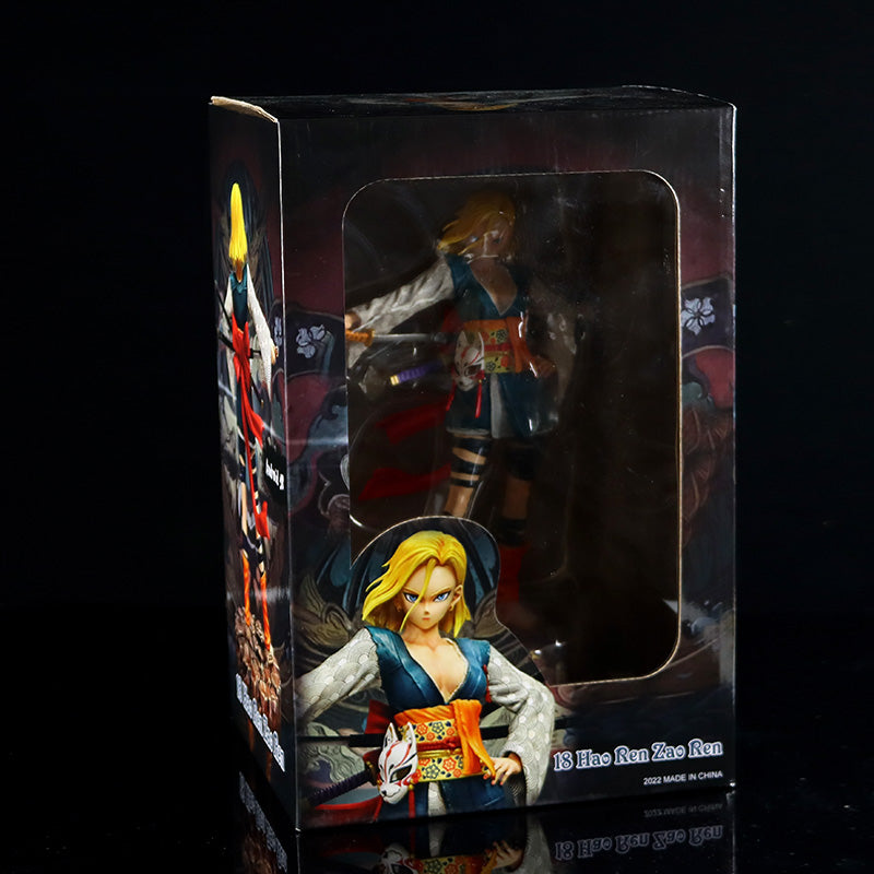 A boxed Seakoff Android 18 Collectible Figure – Dragon Ball Z, is set against a black background. The 26cm anime-style figure features Android 18 with blonde hair in a samurai pose, wearing a blue and orange outfit and holding a sword. The box includes text and logos.