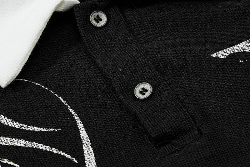 Black ribbed polo shirt with white contrast collar, skull print details, and two button placket close-up