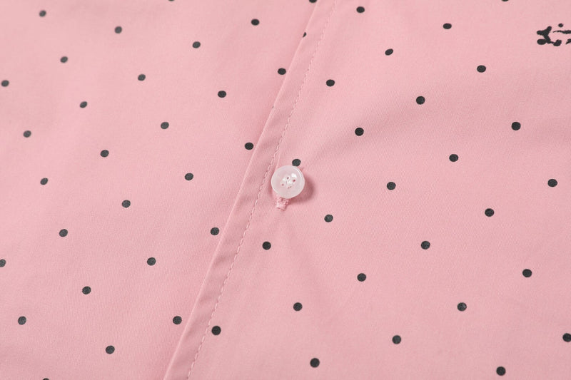 Close-up of pink shirt button placket with black polka dots