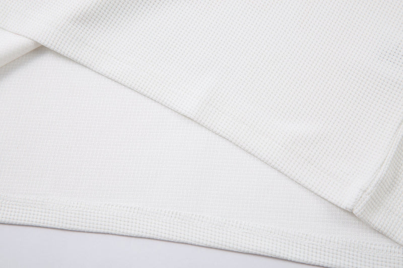Close-up of white waffle knit hem and sleeve edge on the long sleeve tee