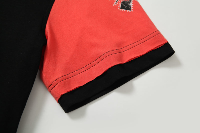 Close-up of a red and black patchwork crop tee sleeve with contrast stitching and graphic detail