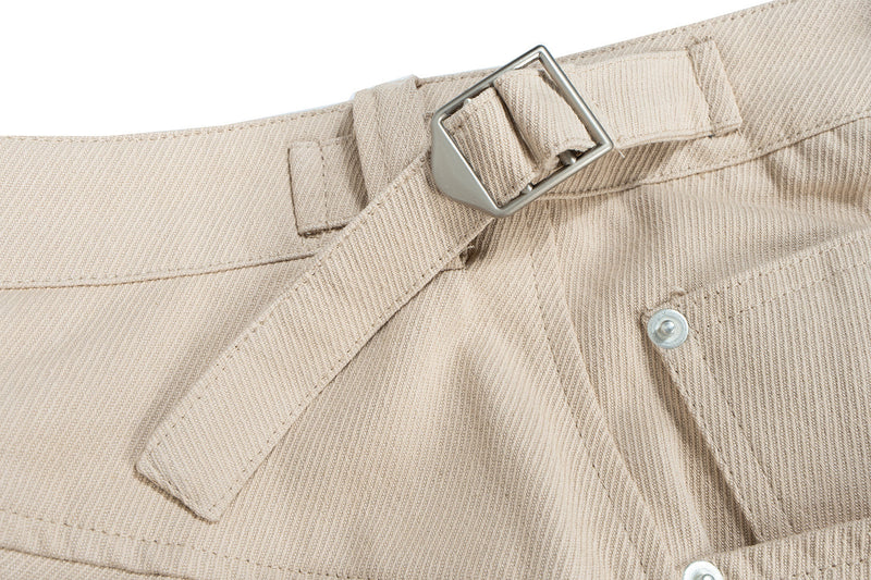 Close-up of beige shorts waistband buckle and pocket stitching detail