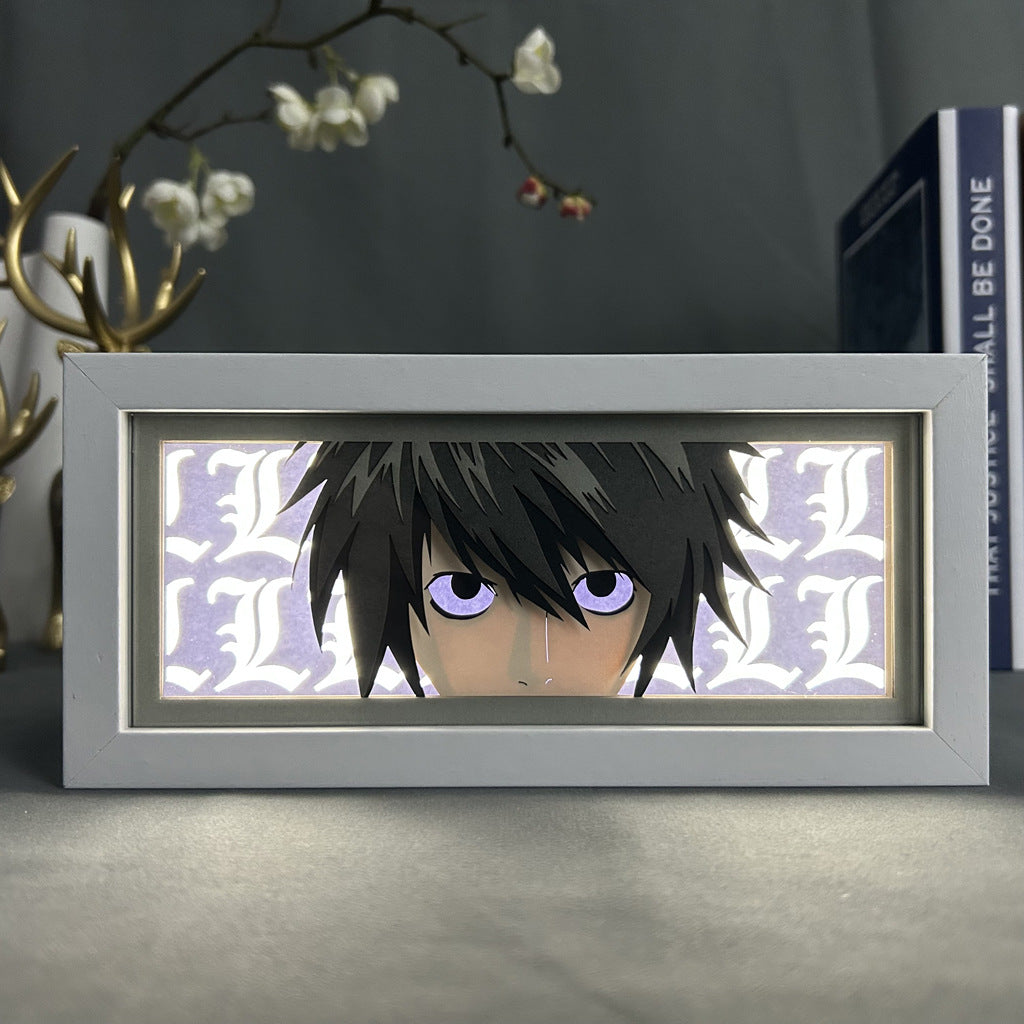 The Death Note Anime Light Box, featuring L (Lawliet) in anime-style with dark hair and purple eyes, includes a 3D-effect white &quot;L&quot; pattern background. A decorative floral branch and book enhance the scene. This 16-color adjustable LED light is a product of the Death Note brand.