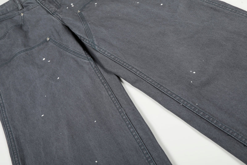 Diagonal close-up of gray wide-leg jeans showing front and leg panels with paint splatter details