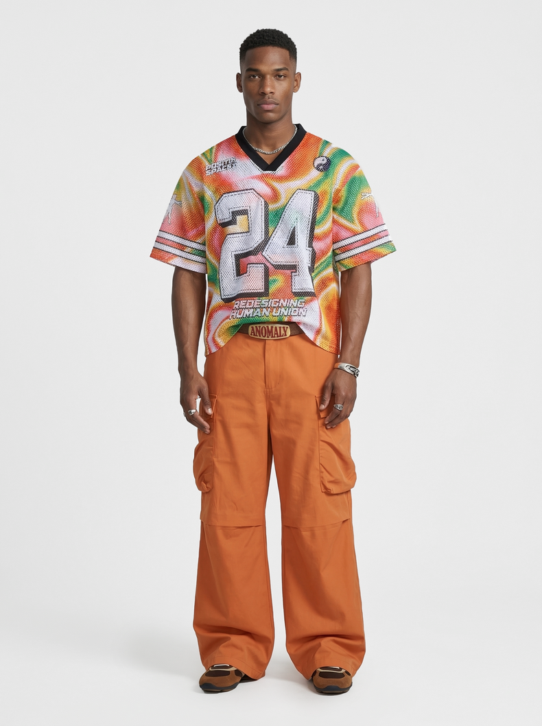 Model wearing a colorful gradient mesh jersey T-shirt with oversized 24 graphic and orange cargo pants on a white background
