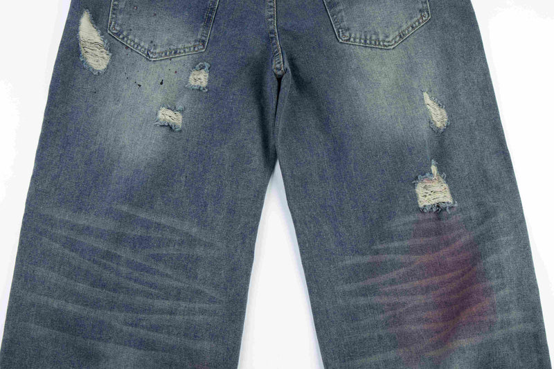 Close-up of the back leg panels on wide-leg jeans with small and large ripped details