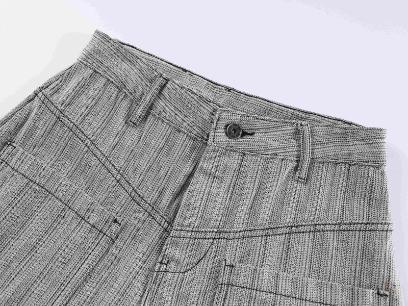 Close-up of gray pant waistband with button, belt loops, and textured woven fabric