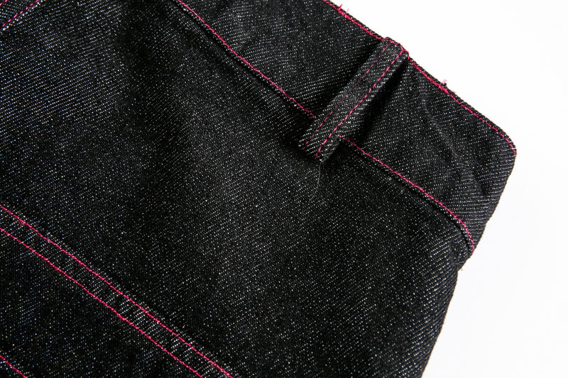Close-up of black denim hem and side seam with red stitching