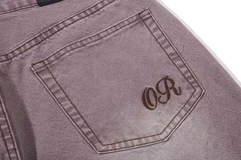 Close-up of brown denim back pocket with embroidered logo