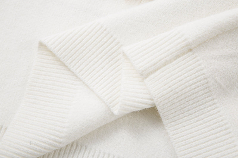Close-up of white sweater cuff with ribbed knit texture and seams