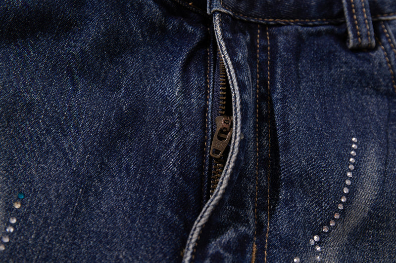 Close-up of zipper fly and rhinestone wave detail on mid-blue denim jeans