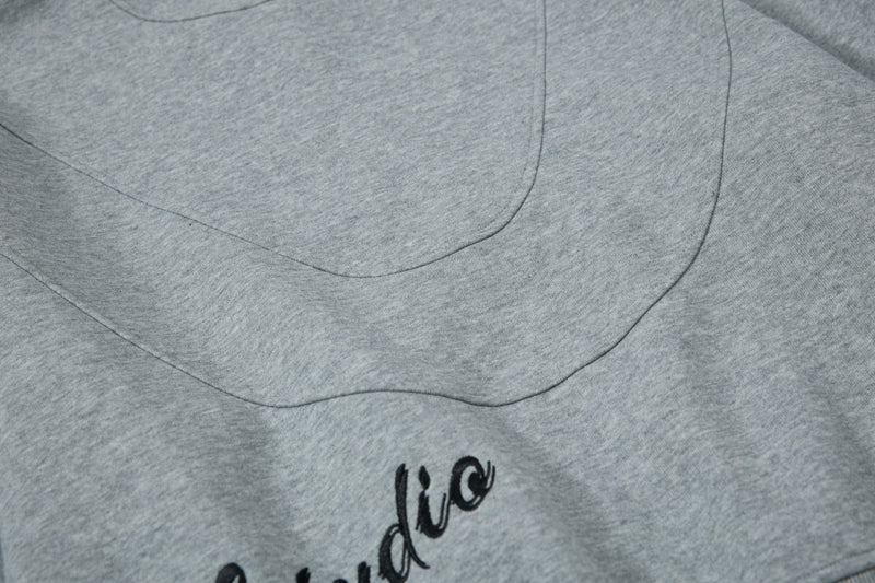Close-up of curved chest panel seam and partial graphic on gray hoodie