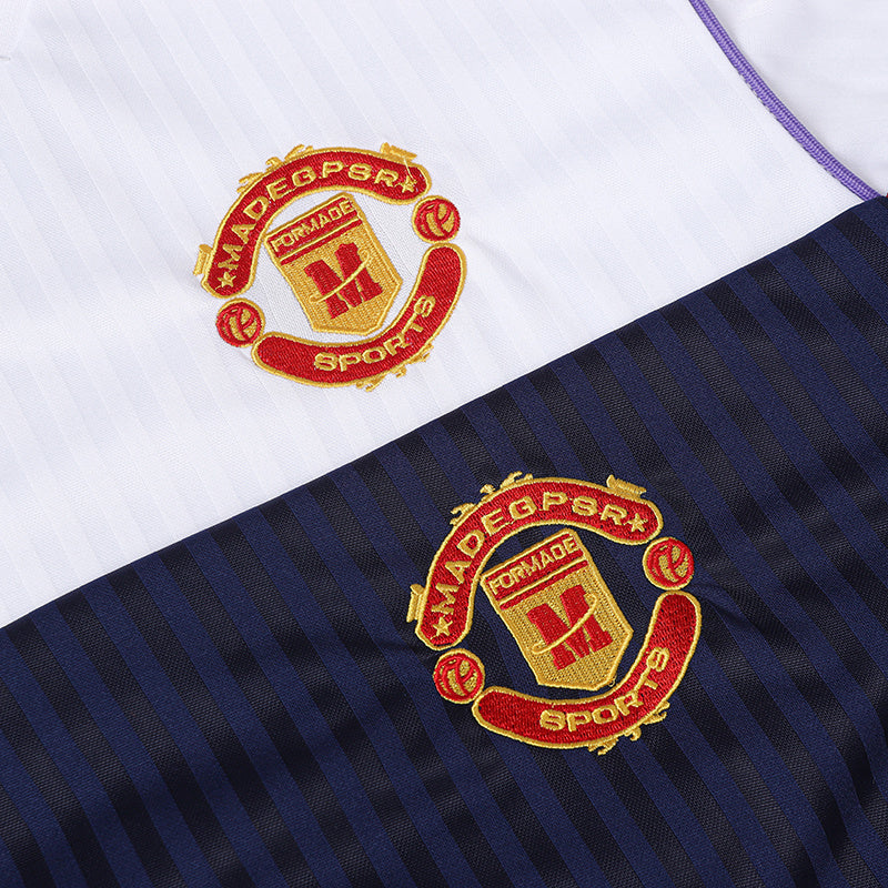 Close-up of a white and navy striped soccer jersey with embroidered red and gold crest logo details