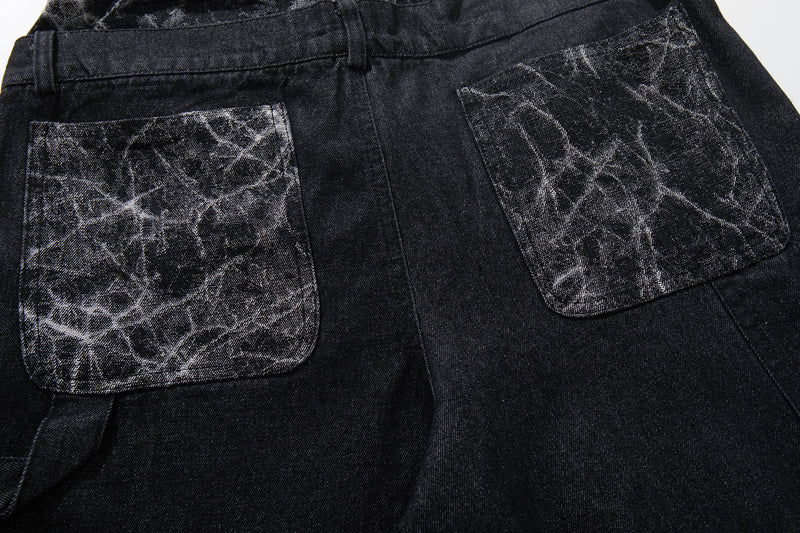 Back pocket close-up of black wide-leg denim pants with cracked panel patch pockets