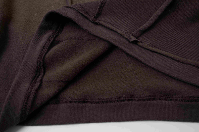 Close-up of a dark brown cotton tee with raw seam paneling and sculpted layered stitching
