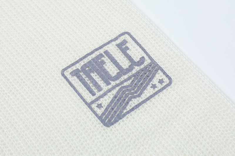 Close-up of crest logo print on cream mesh long sleeve tee