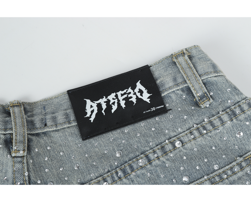 Close-up of the black waistband label on light-wash rhinestone jeans