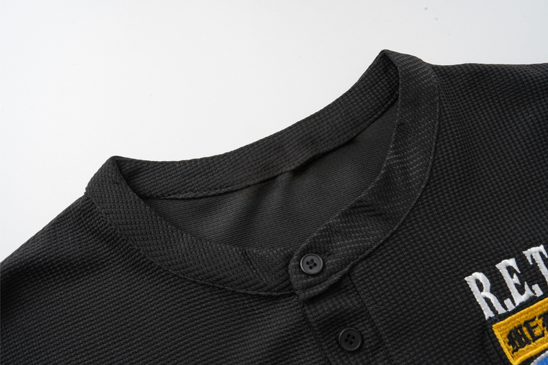 Close-up of black Henley collar and button placket on waffle-knit fabric