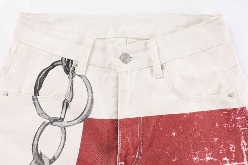 Front waist of cream jeans with belt loops, button fly, and chain print near the pocket