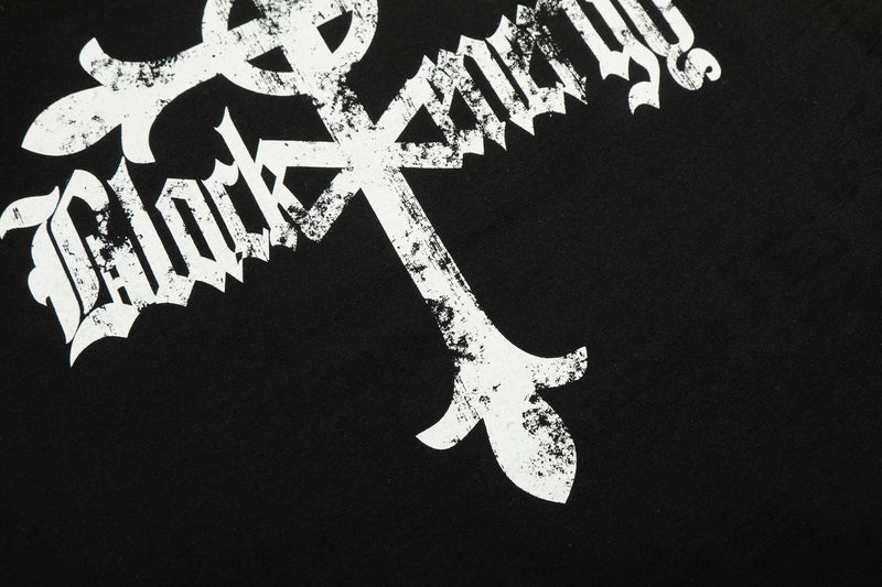 Close-up of distressed cross and gothic lettering graphic on black tee