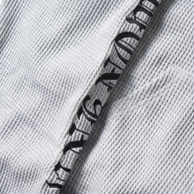 Close-up of black printed lettering along the sleeve on the gray waffle knit hoodie