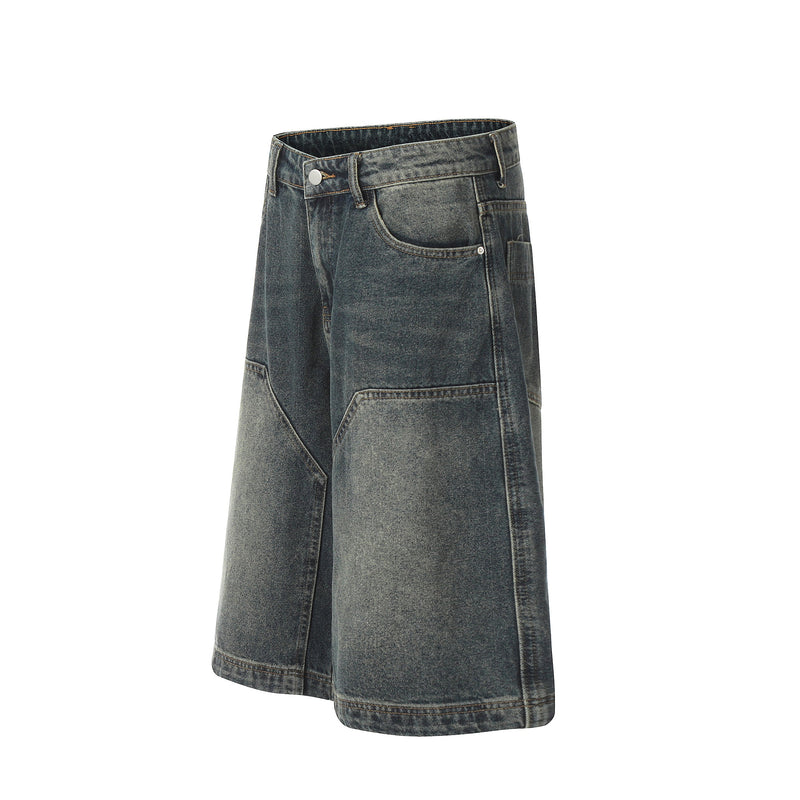 Angled front view of dark wash denim shorts with a button waist and geometric panel details