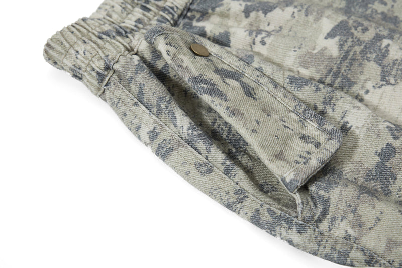 Close-up of camo cargo pants pocket with flap and button snap on the leg