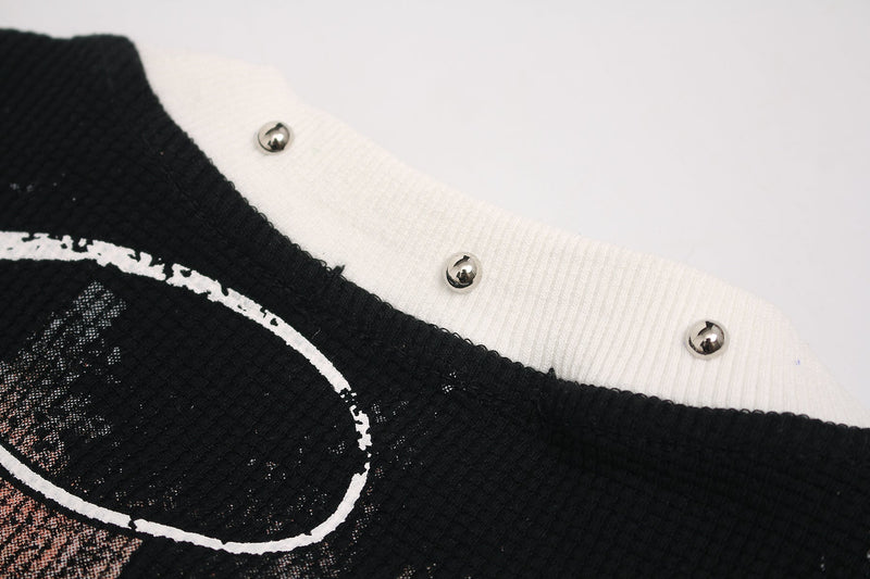 Close-up of a black and white gothic graphic tee with distressed cross script and metallic stud details