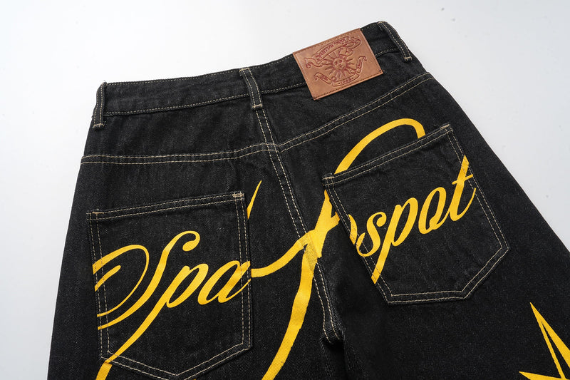 Back waist of black jeans showing tan patch and yellow script print