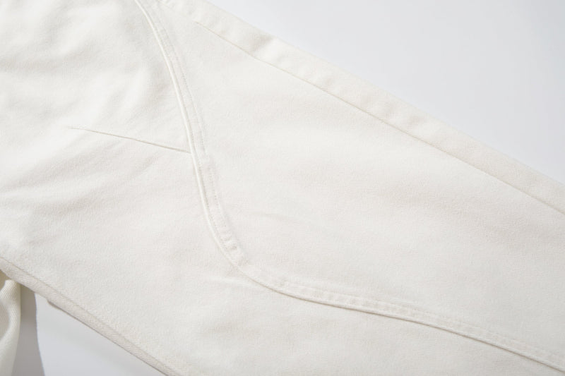 Close-up of the curved seam detail on white denim leg