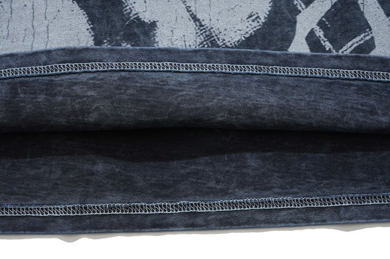 Close-up of a vintage washed black gothic graphic T-shirt hem with visible raw stitching and distressed fabric texture