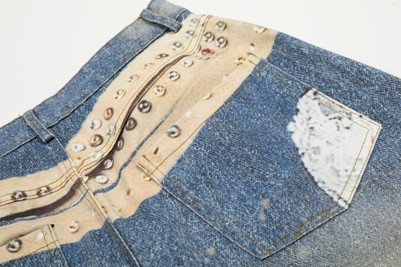 Rear waistband close-up of blue denim jeans with studded print and back pocket