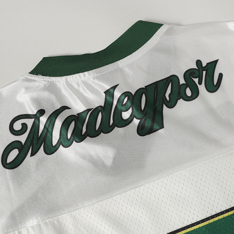 White varsity football jersey with green collar and bold dark green Madepens script across the back