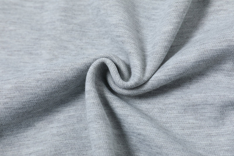 Close-up of light gray oversized tee fabric with geometric seam detail and soft textured knit drape