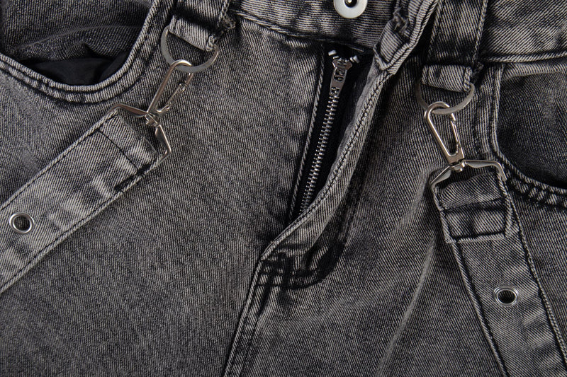 Close-up of front waistband and zipper on washed black jeans with metal strap clips