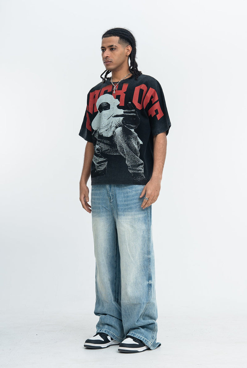 Black oversized graphic tee with bold red lettering and vintage-style print, styled with baggy faded jeans and sneakers