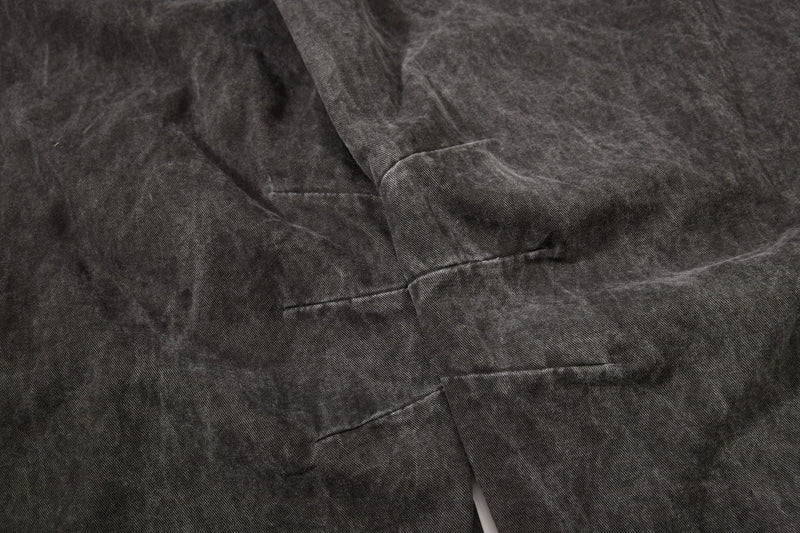 Dark charcoal denim fabric close-up with washed texture and stitched panel seams
