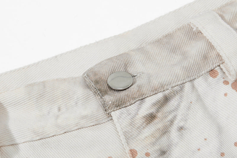 Close-up of the waistband snap button on cream denim jeans