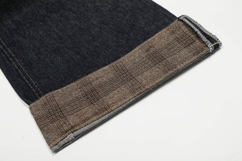 Close-up of cuffed hem on dark wash jeans with contrast plaid trim
