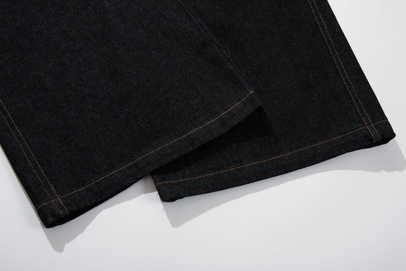 Close-up of the hem on black denim pants with contrast stitching