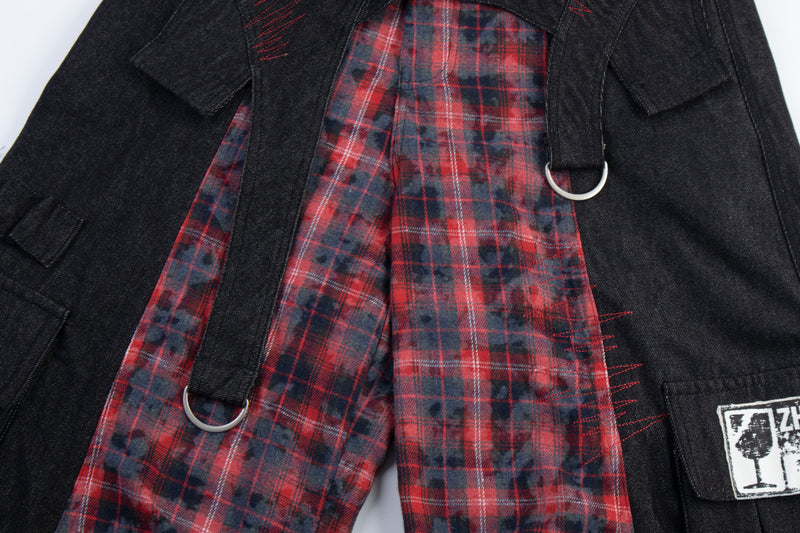 Close-up of red plaid panel and black fabric with hanging strap and metal ring detail