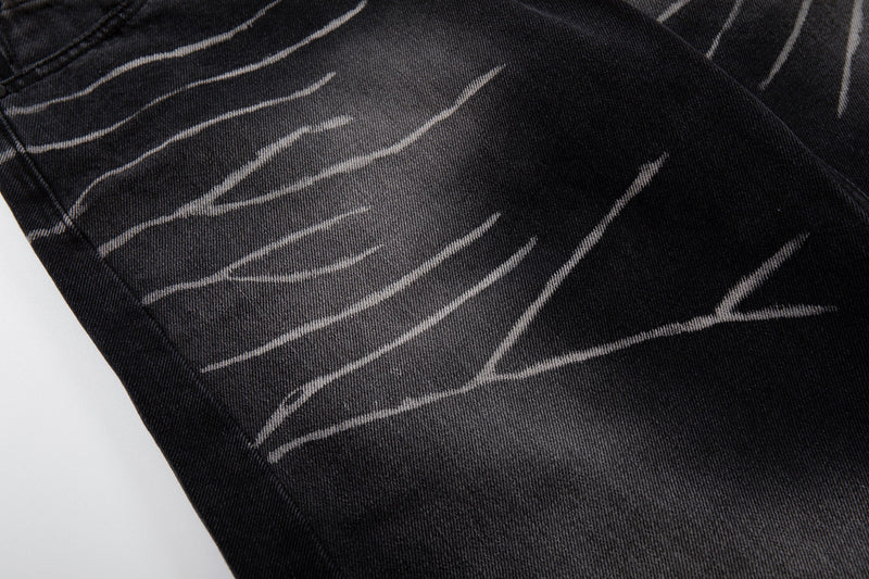 Close-up of washed black denim with scratch-fade streaks across the leg