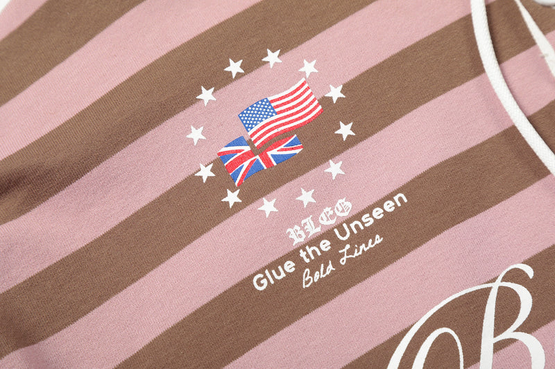 Close-up of small flag emblem and text print on pink and brown striped hoodie front