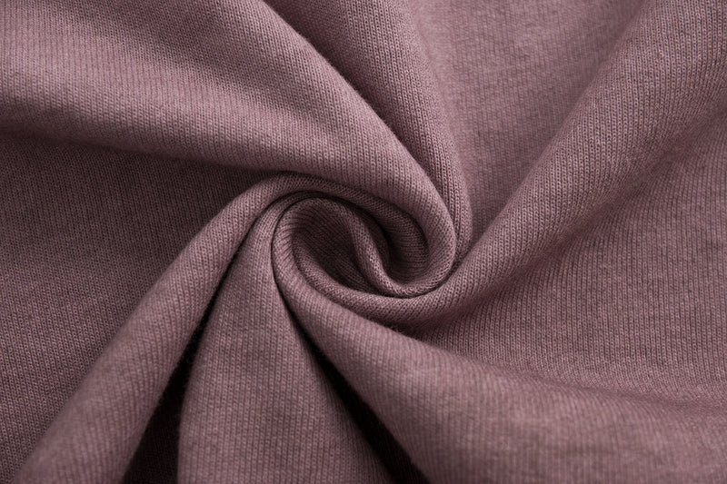 Close-up of dusty mauve vintage wash cotton tee fabric with soft folded texture and spiral drape