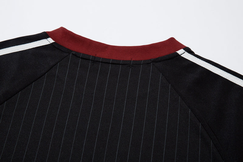 Close-up of black jersey collar with red ribbed neck trim and white shoulder stripe