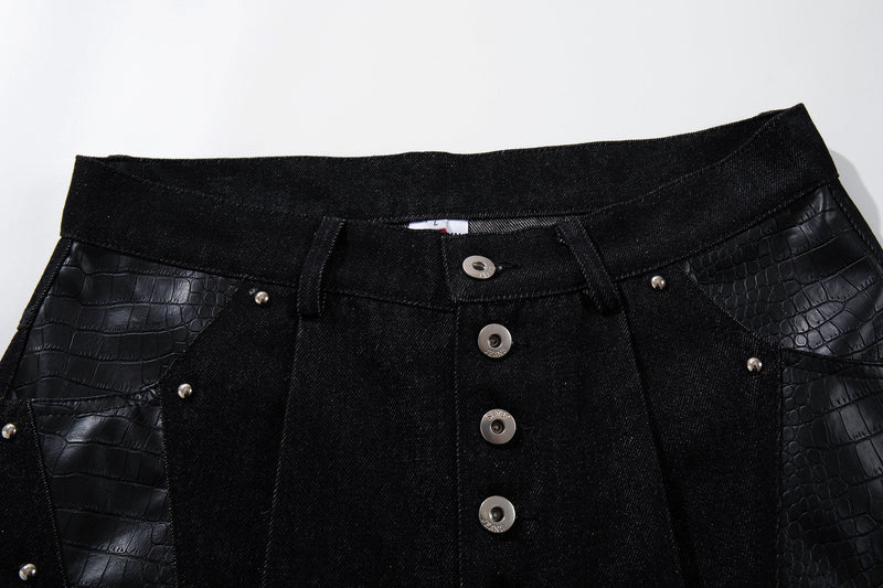 Close-up of black denim waistband and front button fly with crocodile-textured side panels